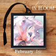 Framed watercolor painting of an iris with a black ribbon on a wooden surface, labeled 'February Iris'.