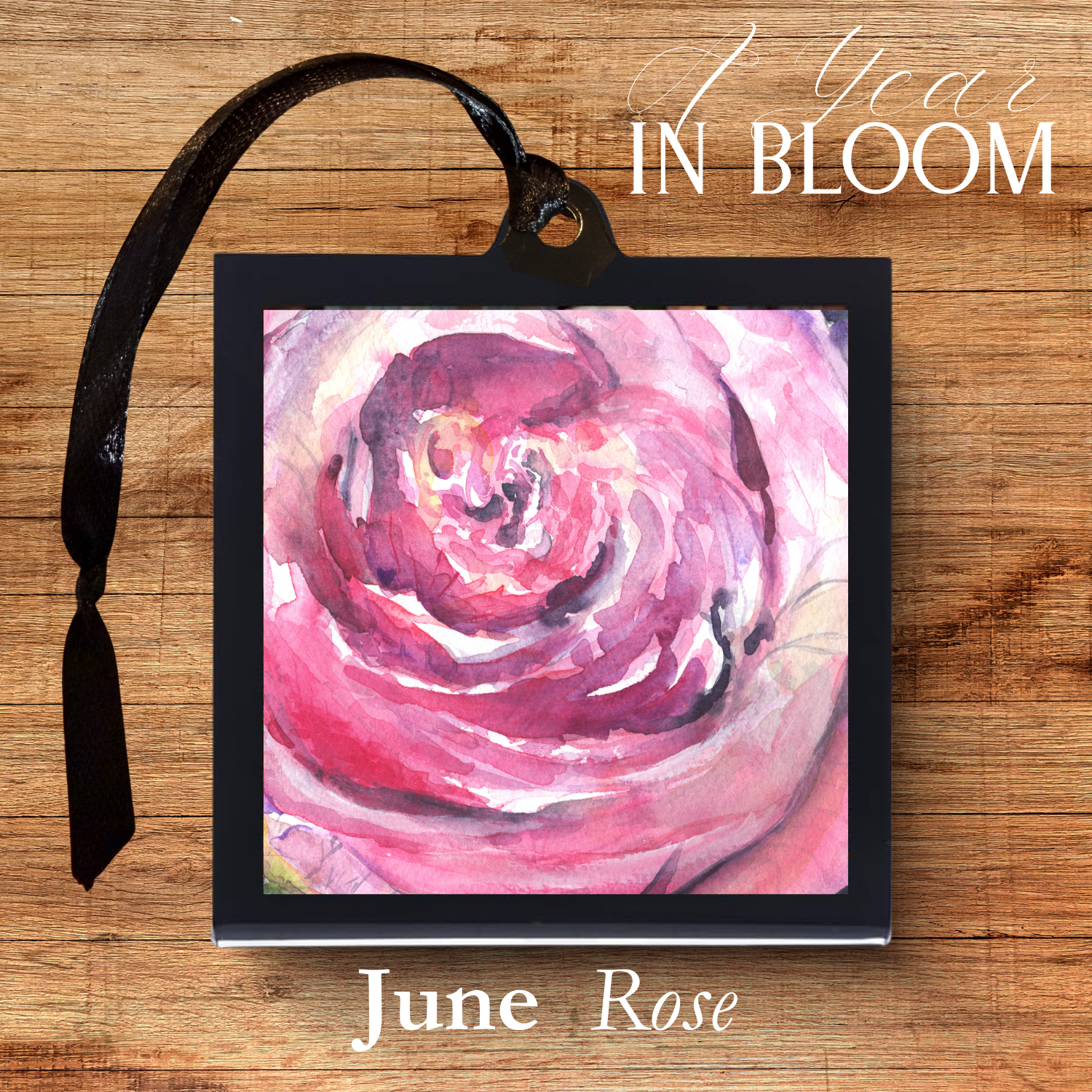 Framed artwork of a pink rose with 'June Rose' text on a wooden surface.