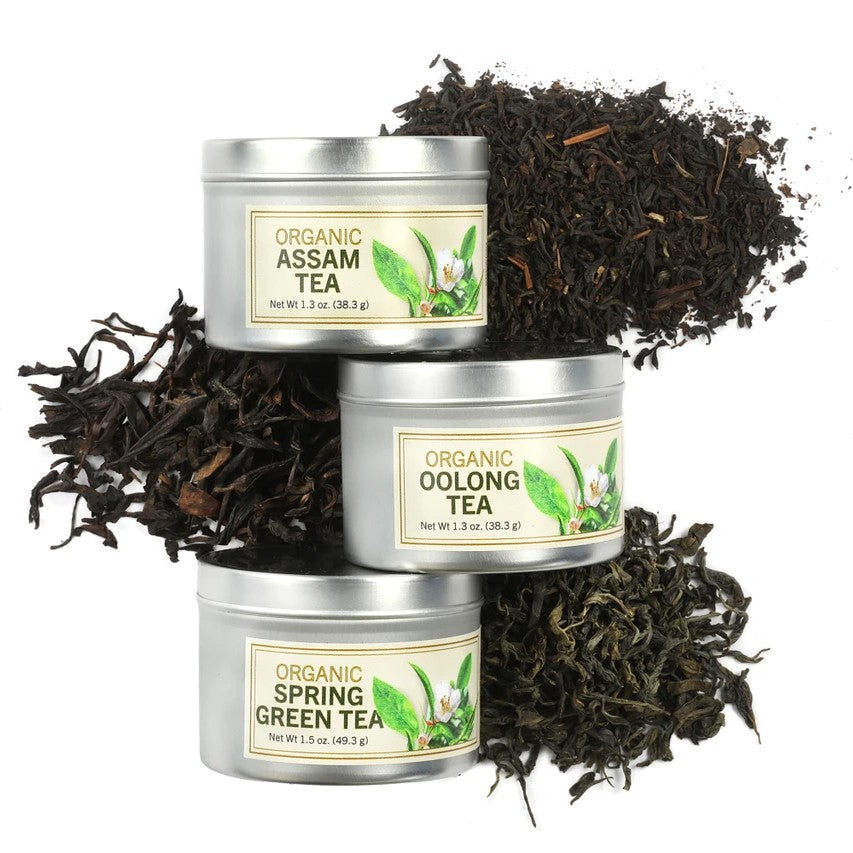Three tins of organic tea with loose tea leaves on a white background