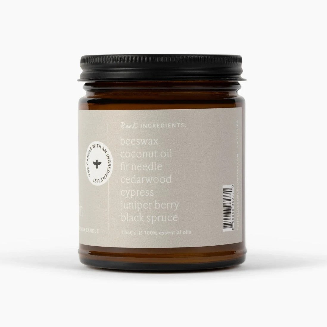 An amber glass jar candle with a black metal lid and a light beige label, shown on a clean white background. The label lists ingredients such as beeswax, coconut oil, fir needle, cedarwood, cypress, juniper berry, and black spruce.