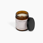 Candle in an amber jar labeled 'Fresh Linen' on a white background
