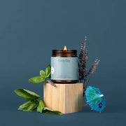 Candle labeled 'Rainy Day' with lavender and a small blue umbrella on a dark background