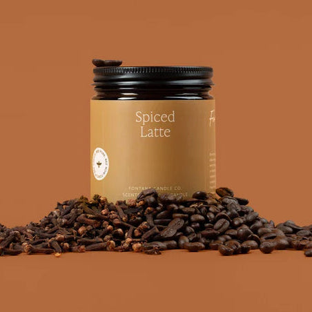 Jar of 'Spiced Latte' candle with clove spices on a brown background
