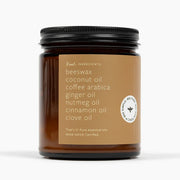 Candle jar with a label listing ingredients on a white background