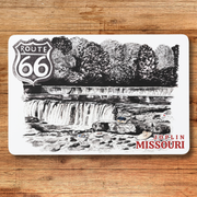 Placemat with Route 66 design featuring a waterfall and Joplin, Missouri text on a wooden surface.
