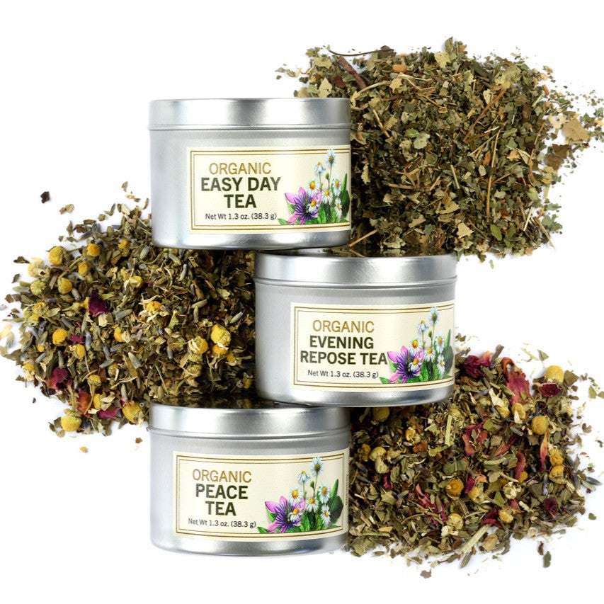 Three tins of organic tea with dried herbs on a white background