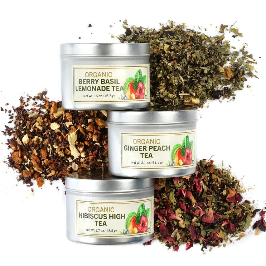 Three tins of organic tea with their respective labels and loose tea leaves on a white background