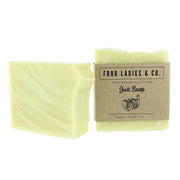 A pale yellow bar of soap shown next to its kraft paper packaging label, which reads 'FOUR LADIES & CO. Just Soap'.