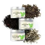 Three organic tea tins with their respective tea leaves displayed on a white background