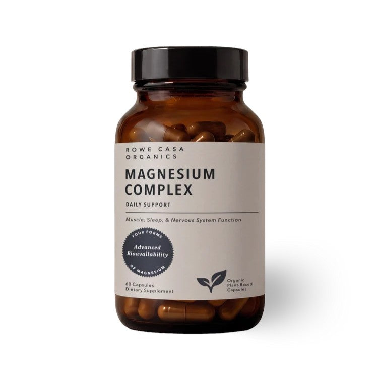 A bottle of Rowe Casa Organics Magnesium Complex dietary supplement, featuring an amber glass bottle with a black cap and a white label.