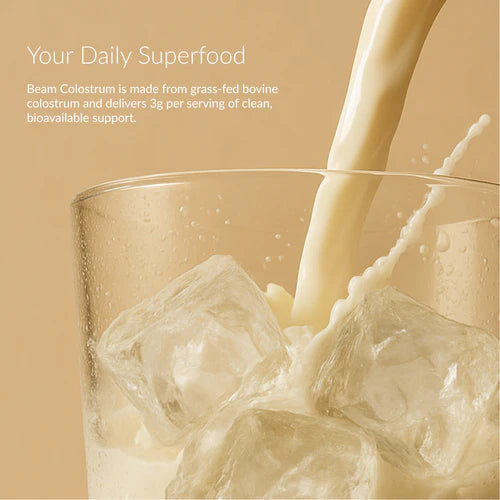 Glass of colostrum with ice cubes being poured, with a beige background and text about Beam Colostrum.