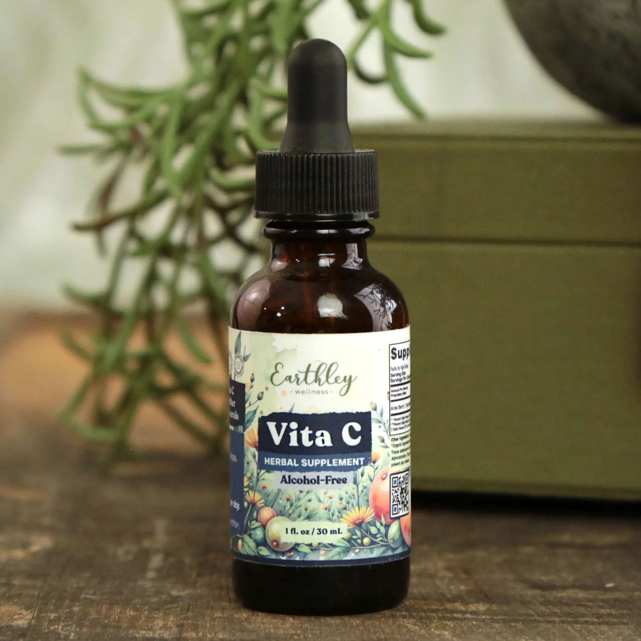 Earthley Vita C supplement bottle with dropper on a wooden surface with a plant in the background