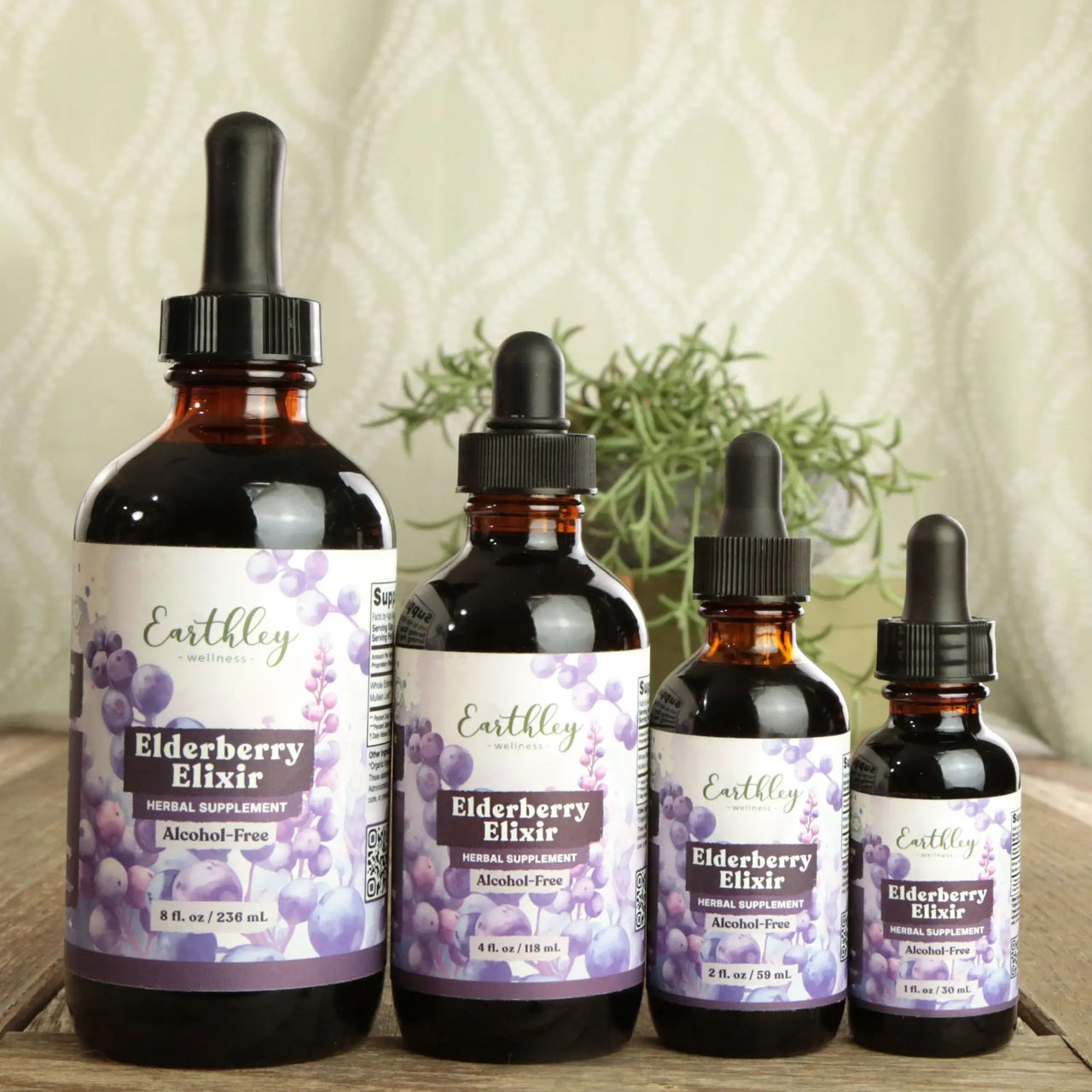 Four bottles of Earthley Elderberry Elixir on a wooden surface with a textured wall background.
