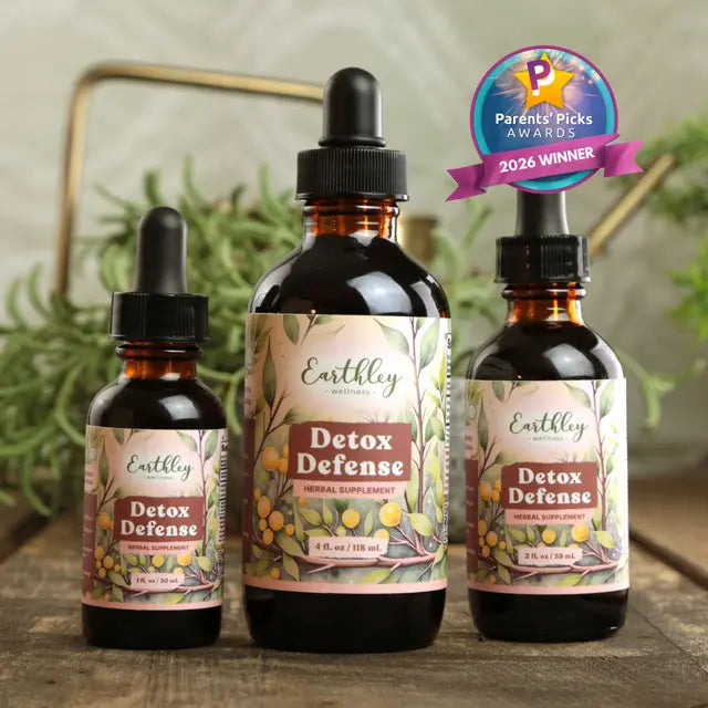 Three bottles of Earthley Detox Defense supplement on a wooden surface with a plant in the background.