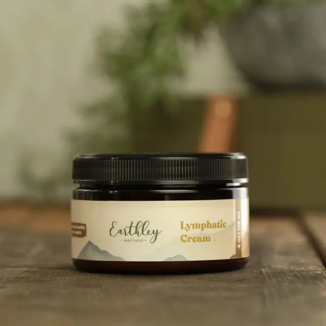 Jar of Earthley Lymphatic Cream on a wooden surface with a blurred plant in the background
