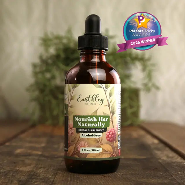 Bottle of Earthley Nourish Her Naturally supplement on a wooden surface with a blurred plant background.