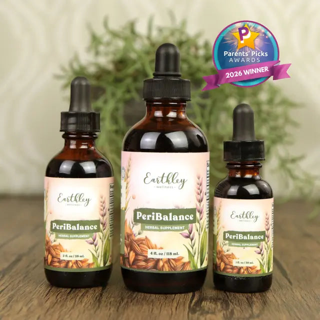 Three Earthly PeriBalance supplement bottles on a wooden surface with a plant in the background.