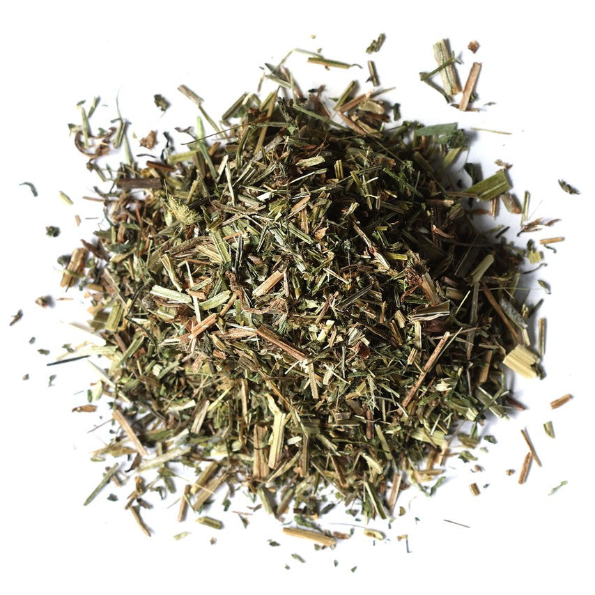 A pile of dried, chopped green herbs or tea leaves on a plain white background.