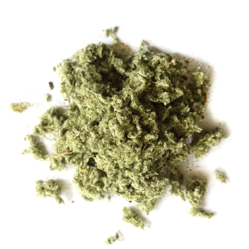A small pile of loose, fibrous green material, likely dried herbs, moss, or craft fiber, photographed on a plain white background.