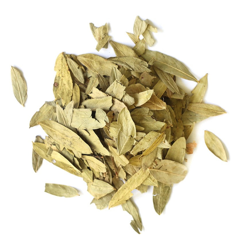 A pile of dried, sliced herbal leaves in light tan and olive-green tones, arranged on a plain white background.