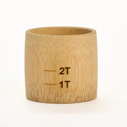 Bamboo measuring cup with '2T' and '1T' markings on a white background