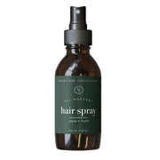 rowe casa Brown glass hair spray bottle with green label on a white background