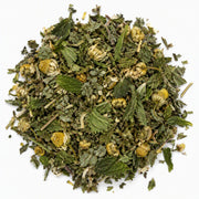 A pile of loose-leaf herbal tea featuring green leaves and dried yellow chamomile flowers on a solid white background.